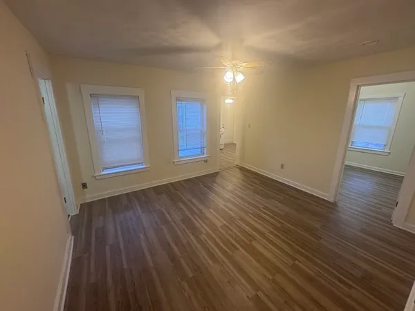an empty room with wooden floor and windows