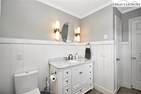 a bathroom with a granite countertop sink two mirror and a toilet