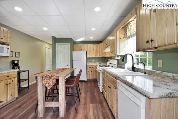 a kitchen with stainless steel appliances granite countertop a table chairs sink and cabinets
