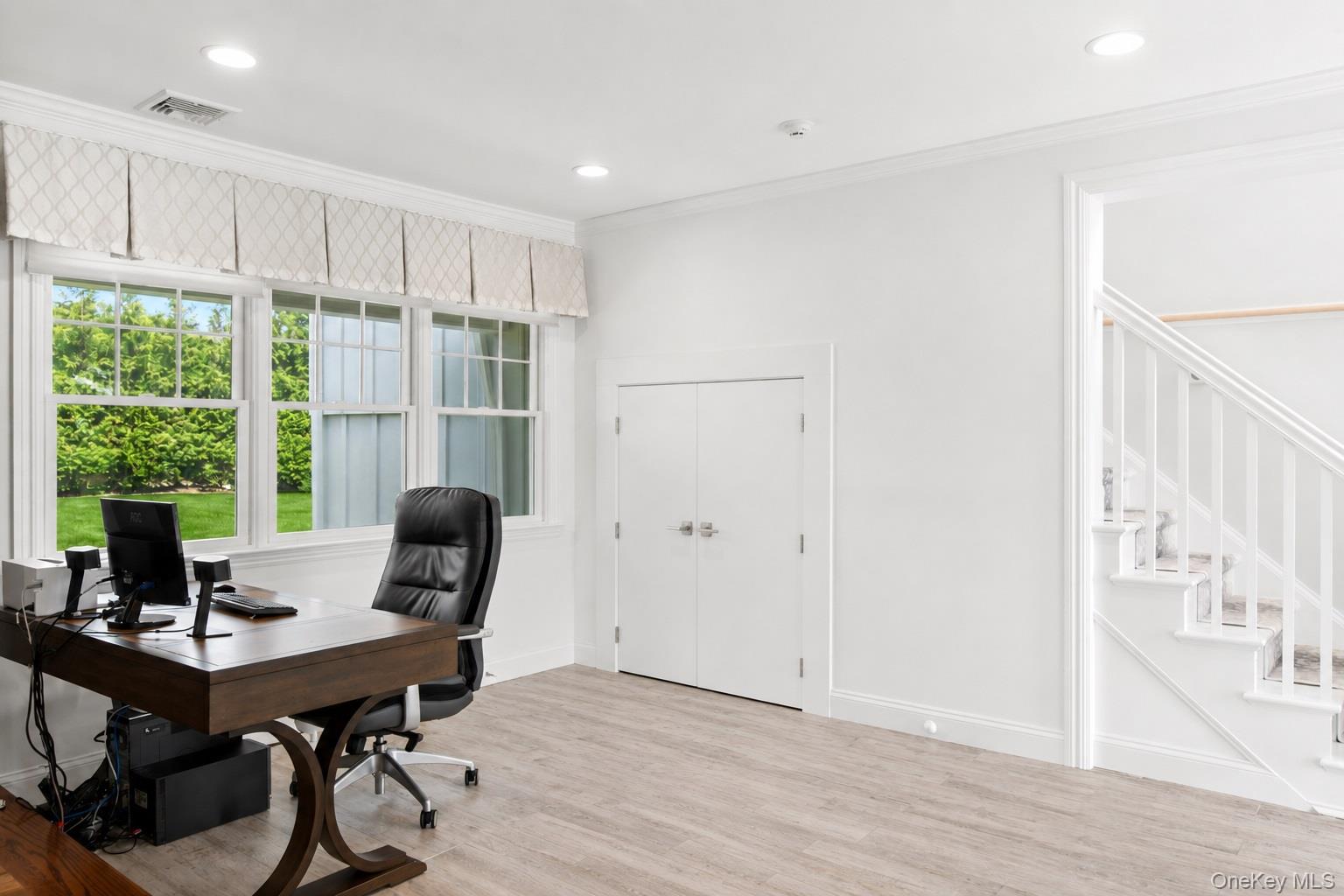 65 Shore Road Westhampton, NY 11977 - Photo 12 of 24 Bright room with light wood-finish flooring, featuring a large triple window with white trim, recessed lighting, and a white staircase with balusters