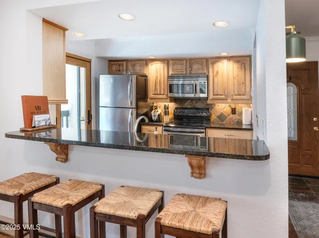 a kitchen with stainless steel appliances granite countertop a sink a stove and a refrigerator