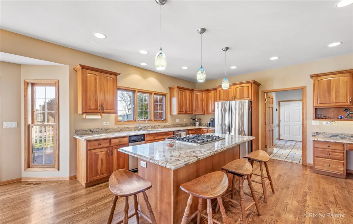 9N523 Kendall Road Elgin, IL 60124 - Photo 9 of 60 a kitchen with stainless steel appliances granite countertop a stove a refrigerator a sink a dining table and chairs with wooden floor