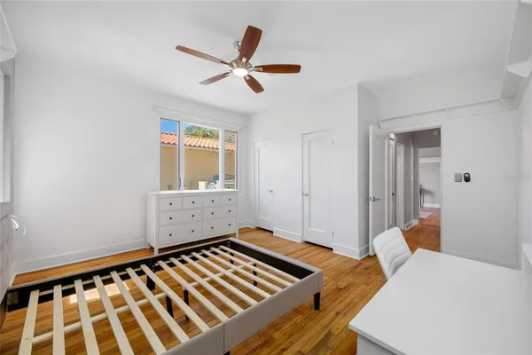 a view of empty room with wooden floor and fan