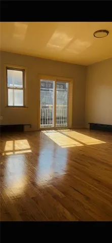 a view of an empty room with window and wooden floor