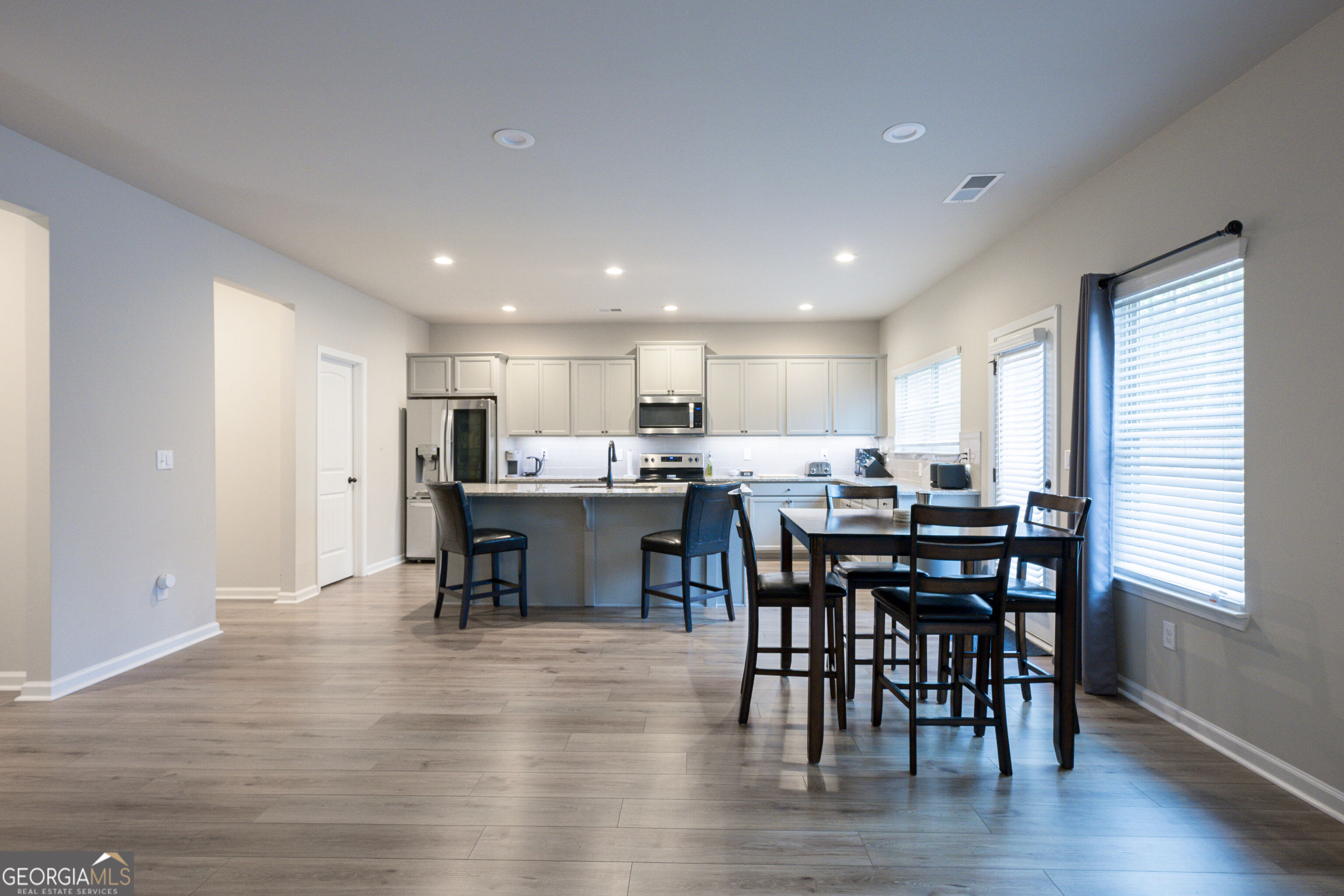 10155 Cormac Street Jonesboro, GA 30238 - Photo 10 of 40 a open dining room with stainless steel appliances wooden floor dining table chairs and window