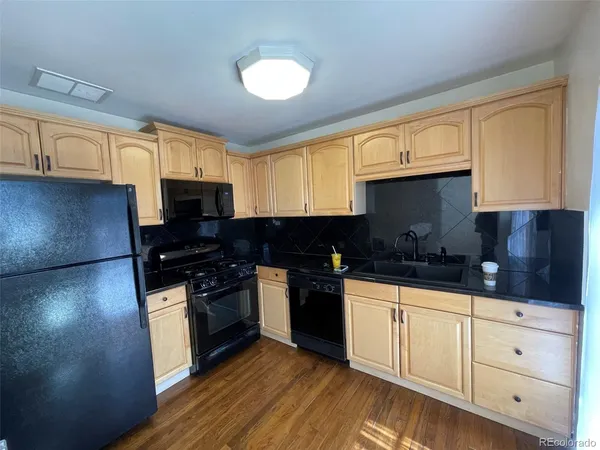 a kitchen with granite countertop a sink cabinets stainless steel appliances and a window
