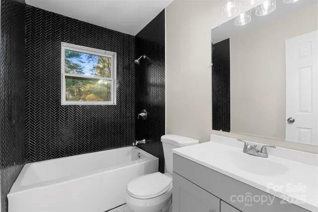 a bathroom with a granite countertop bathtub sink vanity mirror and toilet