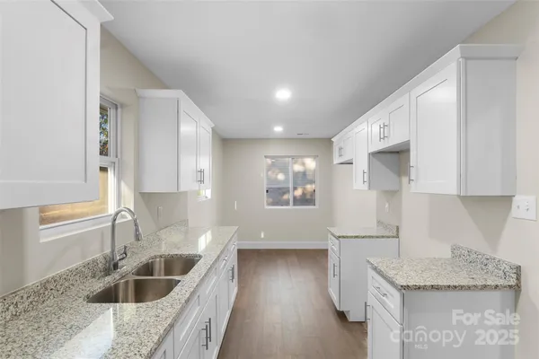 a kitchen with granite countertop a sink a counter space and cabinets