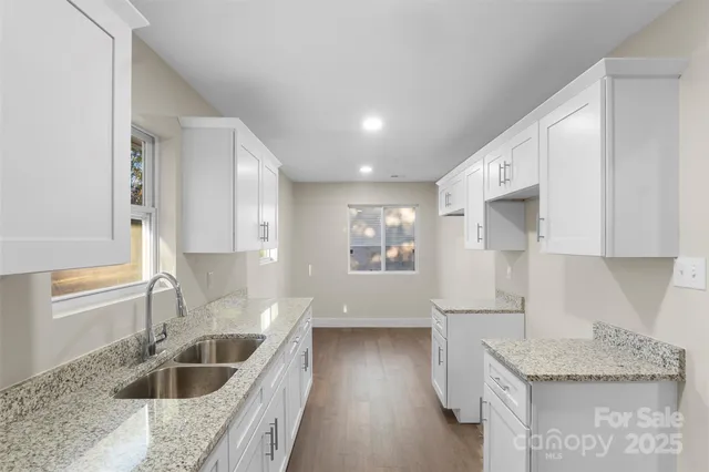 a kitchen with granite countertop a sink a counter space and cabinets