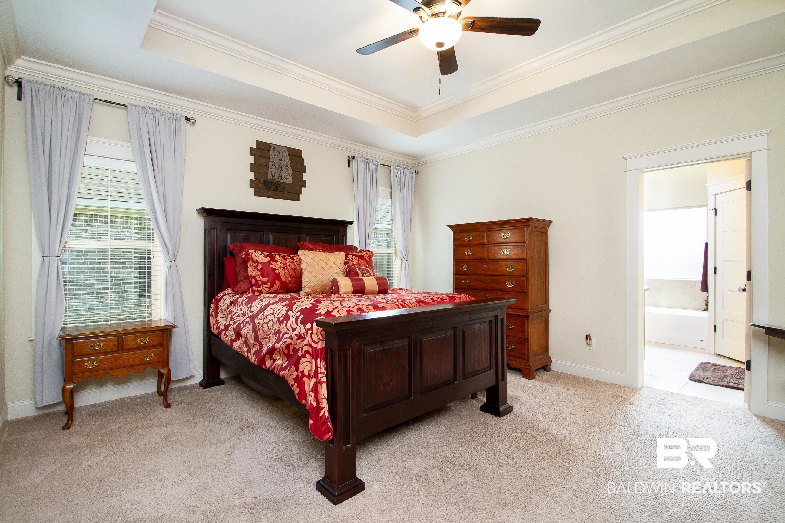 8625 Rosedown Lane Daphne, AL 36526 - Photo 13 of 29 Bedroom featuring light carpet, ensuite bath, a raised ceiling, crown molding, and ceiling fan