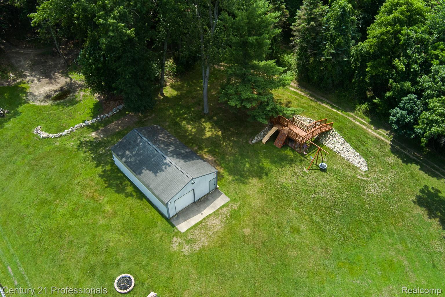 1790 Kent Road Ortonville, MI 48462 - Photo 63 of 64 Expansive green space featuring a detached two-car garage, established trees, and a fire pit