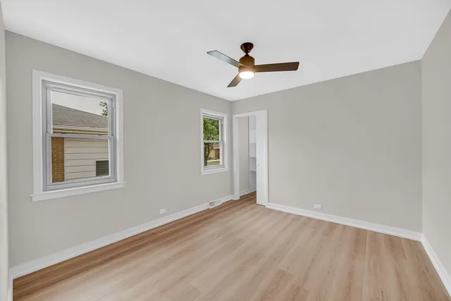 an empty room with a window and a ceiling fan