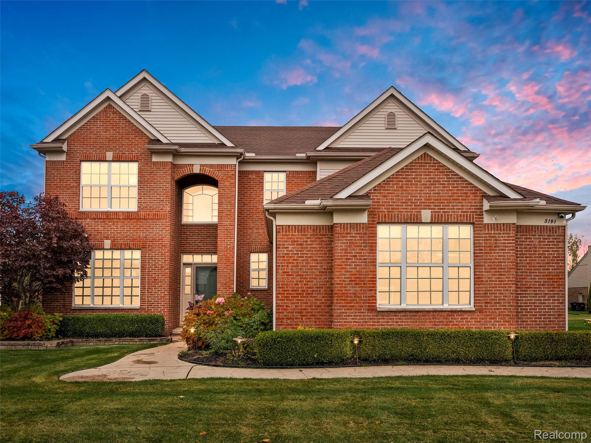 Traditional-style house featuring brick siding, a front yard, and roof with shingles