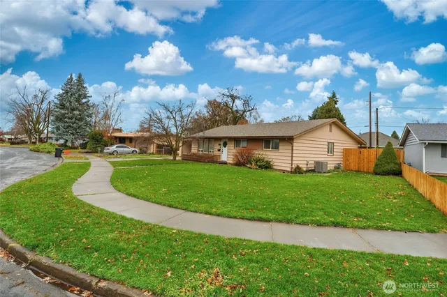 a view of a house with a big yard plants and large trees