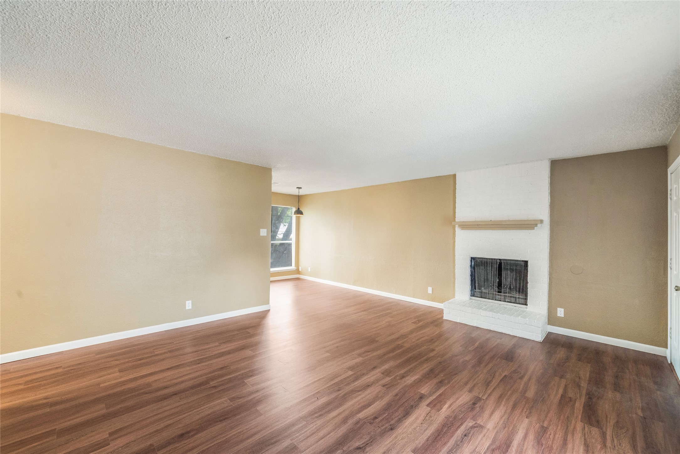 Unfurnished living room featuring a fireplace, a textured ceiling, and dark wood-style flooring