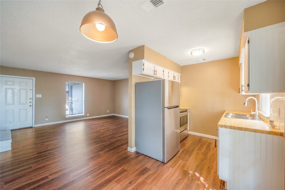 Kitchen featuring appliances with stainless steel finishes, white cabinetry, light countertops, light wood finished floors, and a textured ceiling