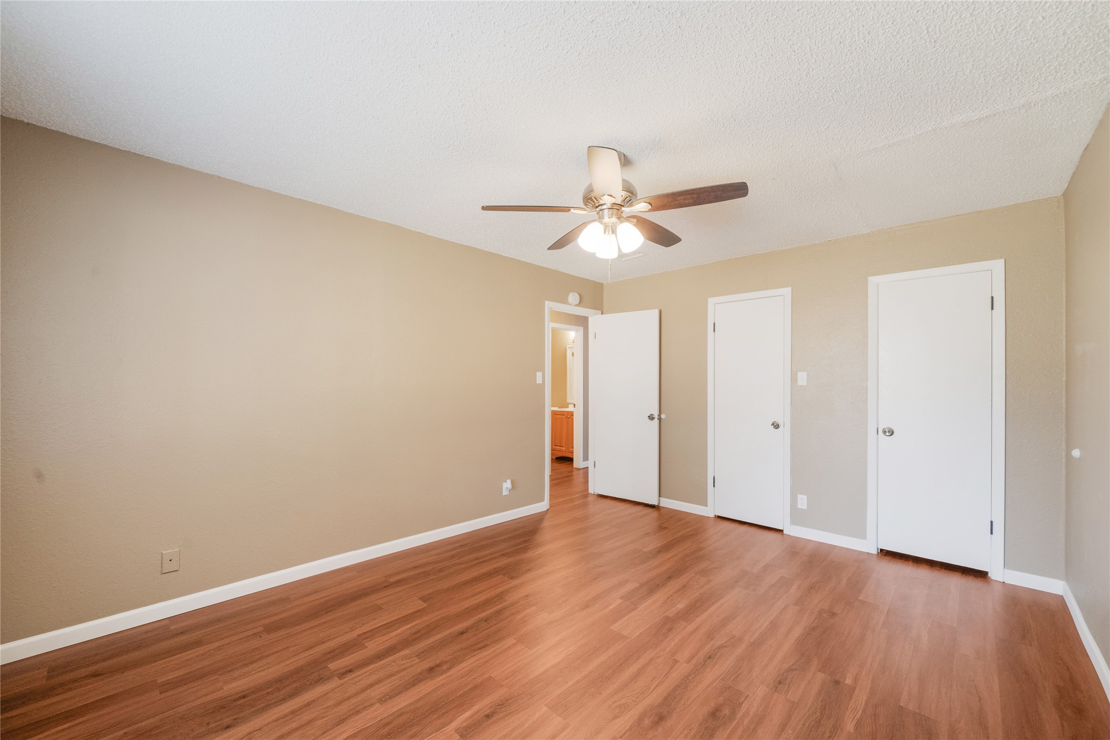 5412 Atascosa Drive, Unit B Austin, TX 78744 - Photo 12 of 15 Unfurnished primary bedroom featuring multiple closets, light wood-style floors, ceiling fan