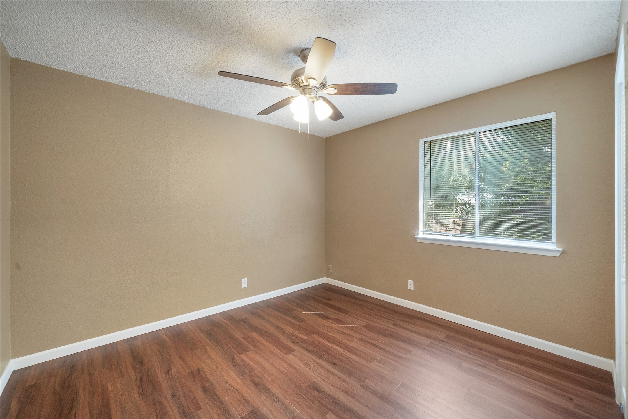 5412 Atascosa Drive, Unit B Austin, TX 78744 - Photo 9 of 15 Unfurnished room featuring a textured ceiling, dark wood-style flooring, and a ceiling fan
