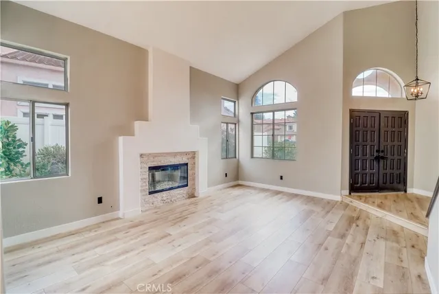 a view of an empty room with wooden floor fireplace and a window