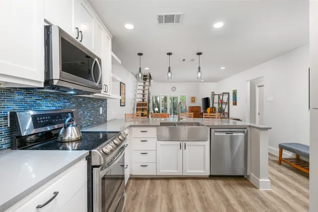 a kitchen with stainless steel appliances granite countertop a stove a sink and a microwave