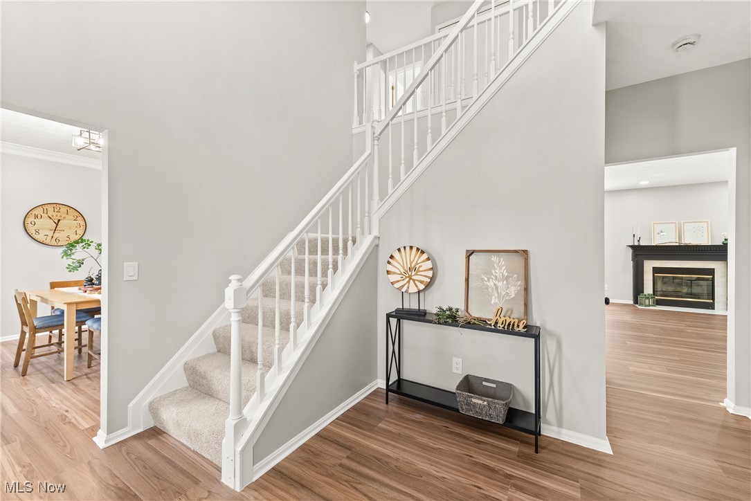 8080 Fair Road Strongsville, OH 44149 - Photo 6 of 50 Staircase with wood finished floors, baseboards, a high ceiling, and a glass covered fireplace