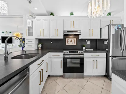 a kitchen with granite countertop a sink stainless steel appliances and white cabinets