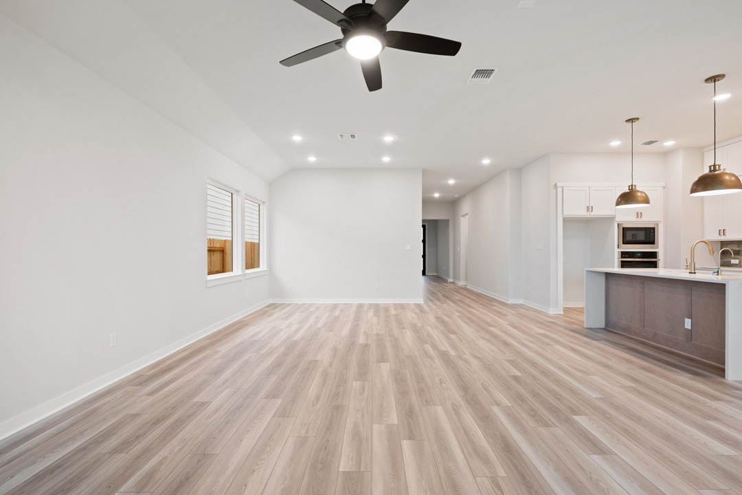 16201 Smithers Road Manor, TX 78653 - Photo 9 of 40 an empty room with wooden floor a ceiling fan and kitchen view