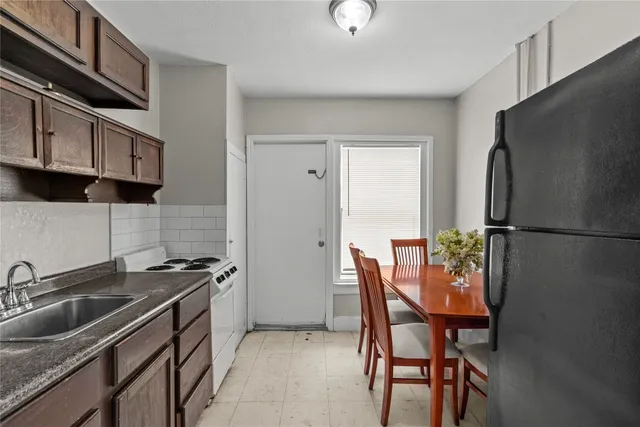 a kitchen with stainless steel appliances a refrigerator a sink a stove a table and chairs