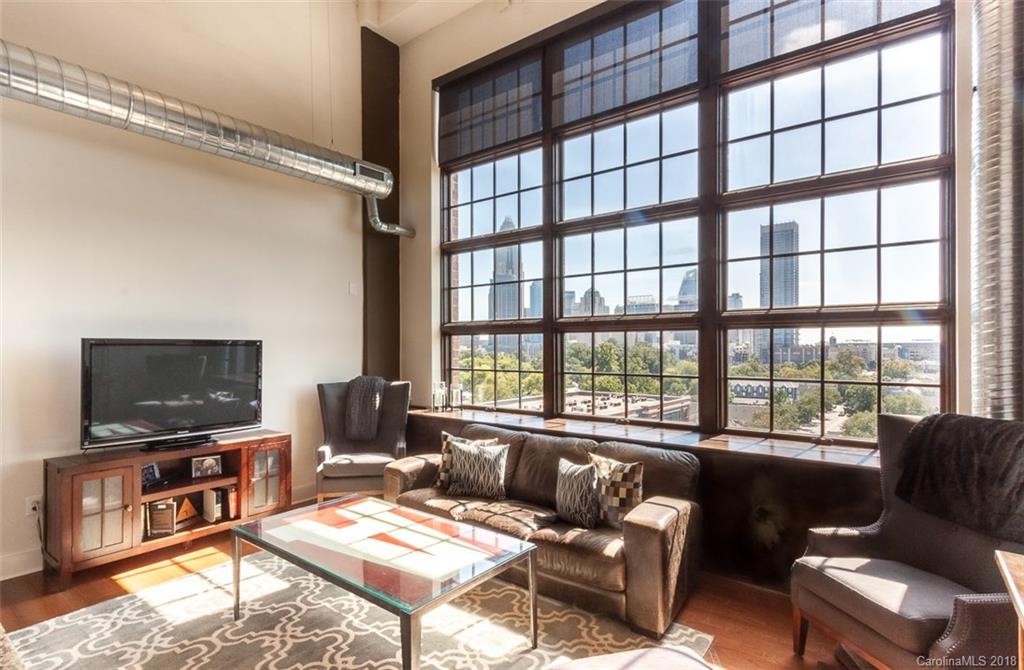 a living room with furniture a flat screen tv and a floor to ceiling window