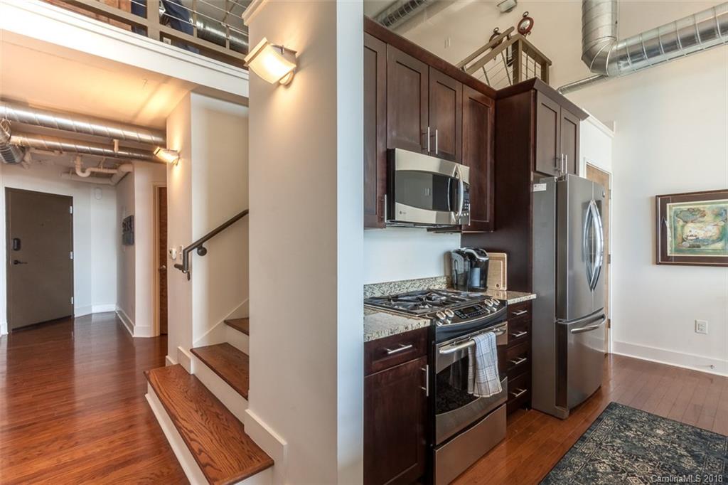 715 North Graham Street, Unit 604 Charlotte, NC 28202 - Photo 3 of 21 a kitchen with stainless steel appliances granite countertop a stove top oven a refrigerator and a sink with wooden floor
