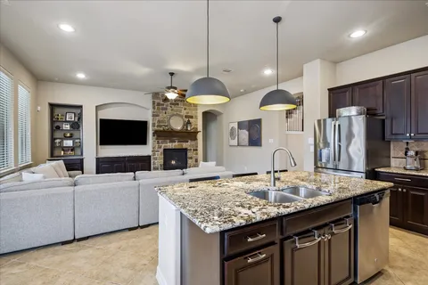 a kitchen with stainless steel appliances granite countertop wooden cabinets a stove a sink a dining table and chairs
