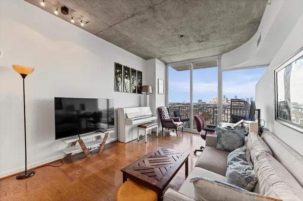 a living room with furniture a flat screen tv and a floor to ceiling window
