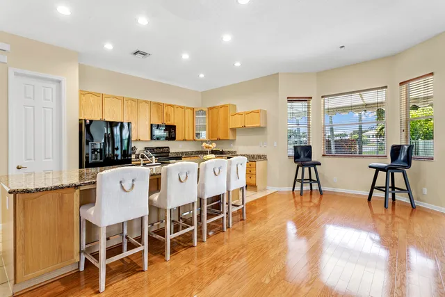 a kitchen with stainless steel appliances kitchen island granite countertop a dining table chairs and granite counter tops