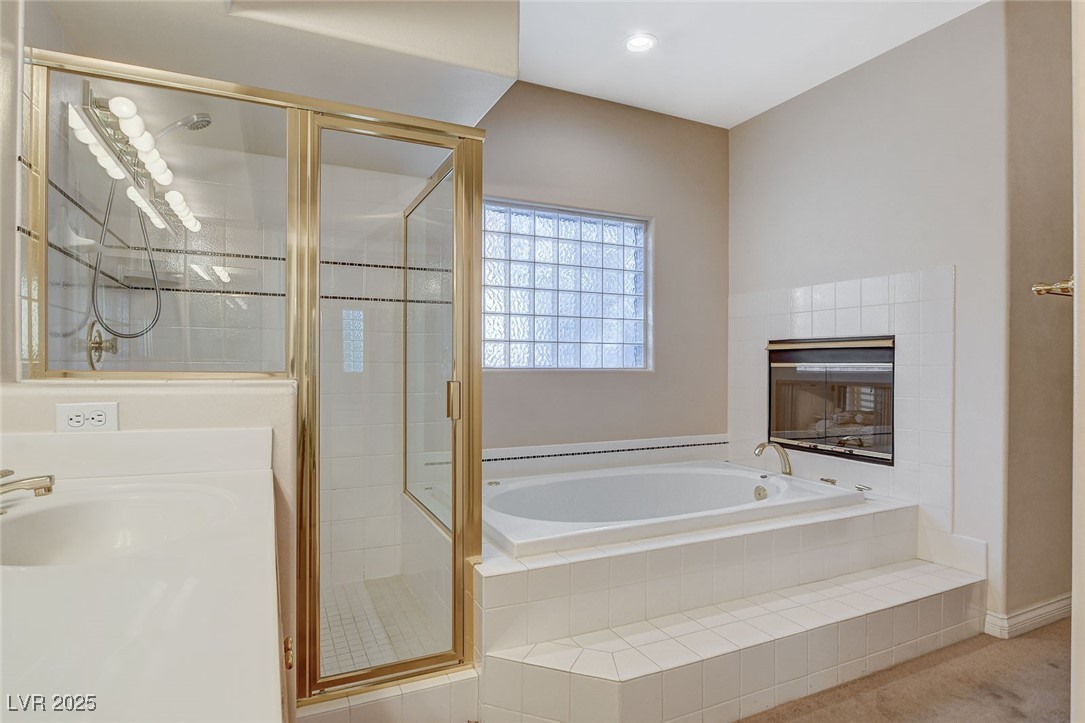 1028 Norellat Road Henderson, NV 89011 - Photo 54 of 74 Primary Bathroom with separate tub and shower and two-way fireplace.