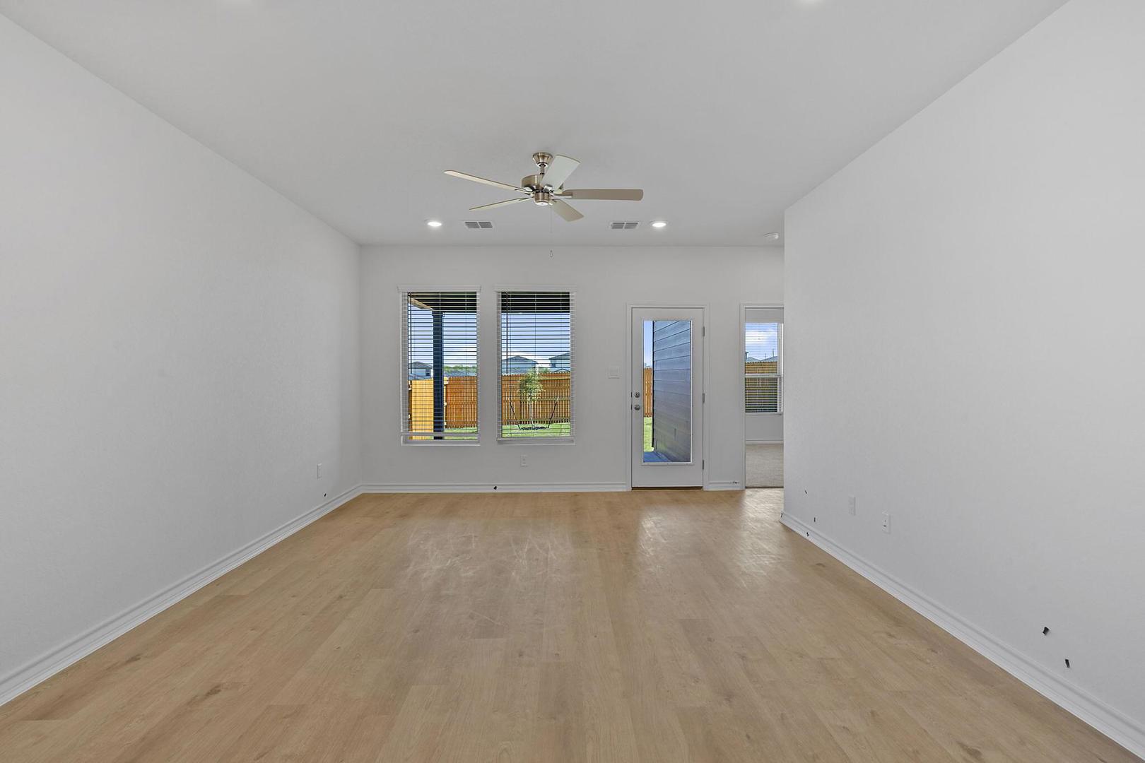 109 Hatari Trail Jarrell, TX 76537 - Photo 9 of 31 Blonde wood flooring and an outdoor connection define this spacious room.