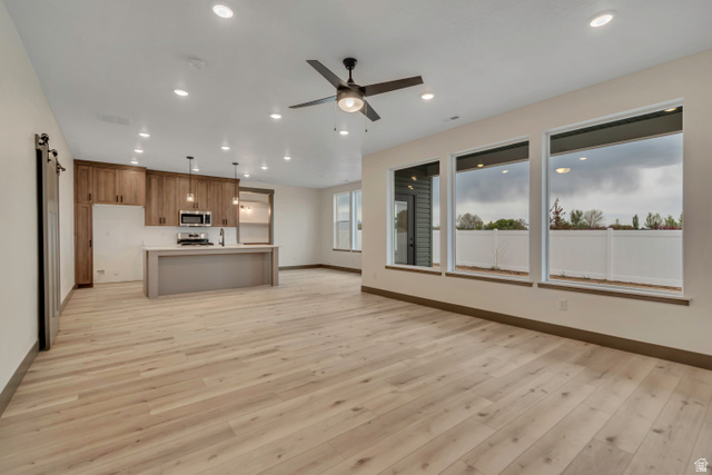 3317 South 1000 West, Unit 6010 Logan, UT 84321 - Photo 33 of 34 Kitchen with open floor plan, an island with sink, light countertops, light wood-style floors, and ceiling fan