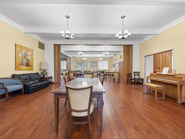 a dining room with wooden floor a chandelier a wooden table and chairs