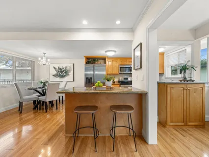 a dining hall with stainless steel appliances granite countertop a dining table chairs with wooden floor