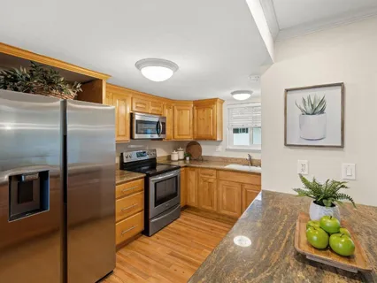 a kitchen with stainless steel appliances granite countertop a refrigerator a stove and a sink with wooden floor