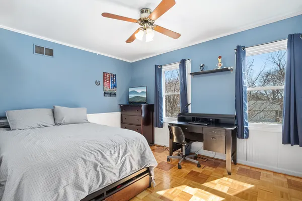 a bedroom with a bed a desk and chair with wooden floor