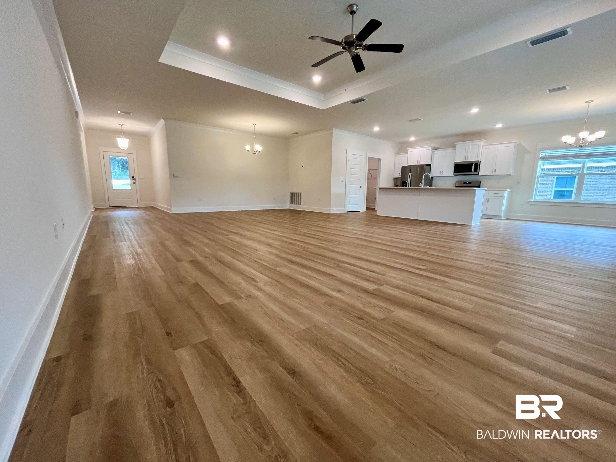 337 Barndling Street Fairhope, AL 36532 - Photo 21 of 34 Unfurnished living room featuring ceiling fan with notable chandelier, a raised ceiling, crown molding, and light hardwood / wood-style flooring