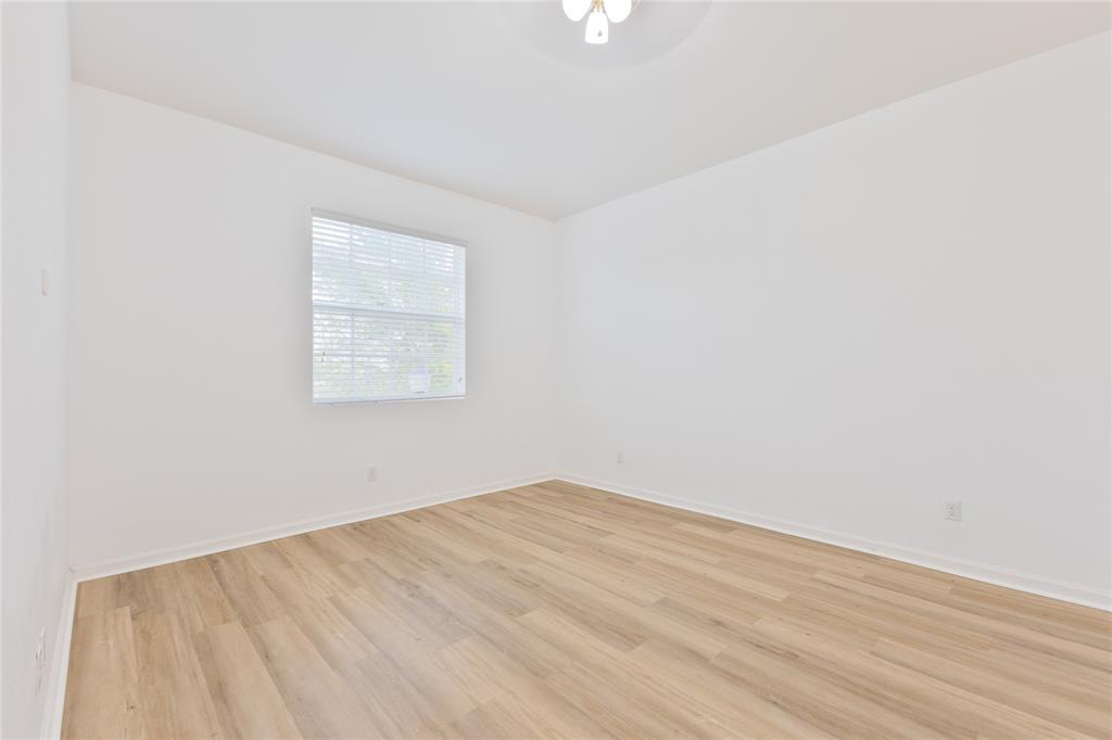 122 Southwest 7th Court, Unit 122 Pompano Beach, FL 33060 - Photo 17 of 36 an empty room with wooden floor and windows