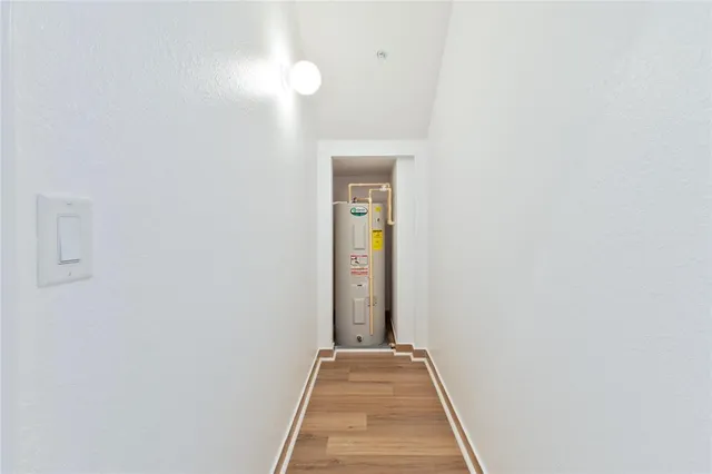 a view of a hallway with wooden floor and a bathroom