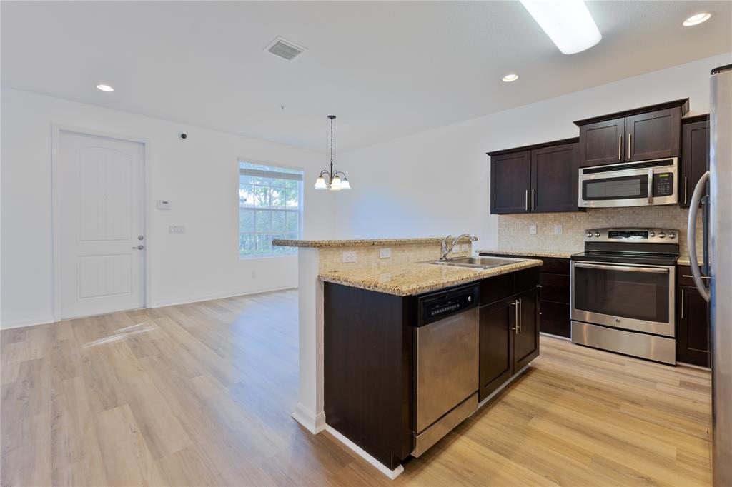 122 Southwest 7th Court, Unit 122 Pompano Beach, FL 33060 - Photo 25 of 36 a kitchen with stainless steel appliances granite countertop a sink and a stove top oven