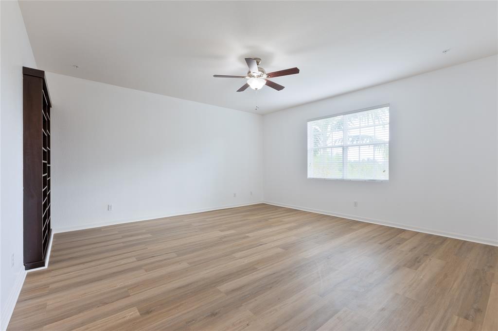 122 Southwest 7th Court, Unit 122 Pompano Beach, FL 33060 - Photo 8 of 36 an empty room with wooden floor ceiling fan and windows