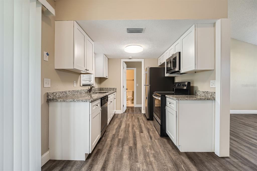7001 Heath Drive Port Richey, FL 34668 - Photo 5 of 11 a kitchen with granite countertop a sink a counter top space stainless steel appliances and cabinets