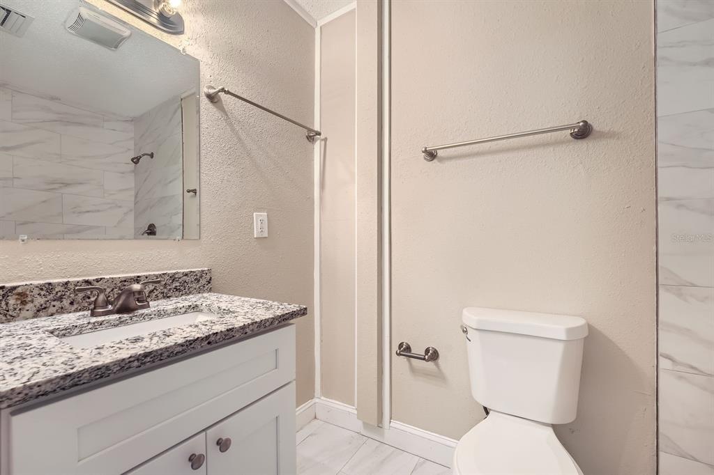 7001 Heath Drive Port Richey, FL 34668 - Photo 7 of 11 a bathroom with a granite countertop sink toilet and shower