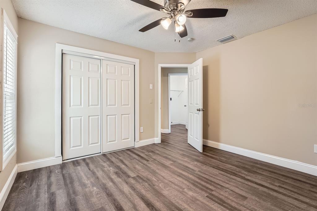 7001 Heath Drive Port Richey, FL 34668 - Photo 8 of 11 an empty room with wooden floor chandelier fan and closet area