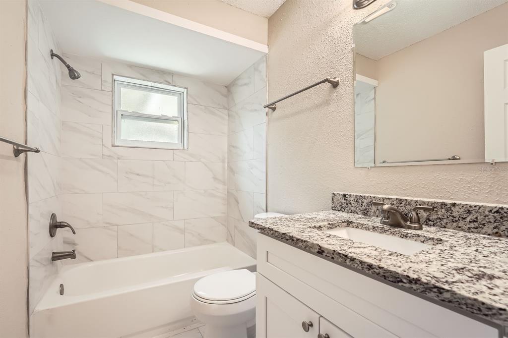 7001 Heath Drive Port Richey, FL 34668 - Photo 10 of 11 a bathroom with a granite countertop sink a toilet and shower
