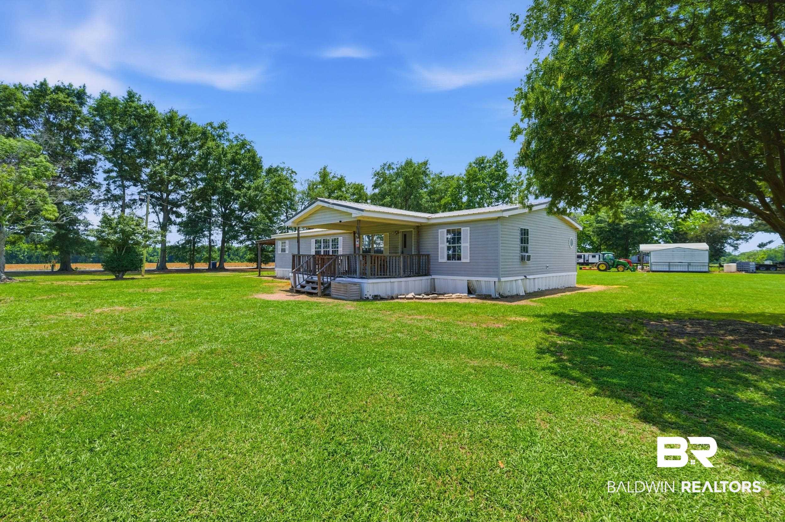 926 Tumbling Lane Atmore, AL 36502 - Photo 4 of 56 Expansive grassy yard surrounding a light-colored property with a covered porch and deck